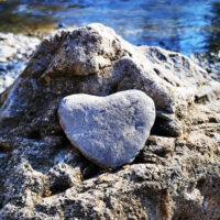 Ein Stein auf Herz ist auf einem grösseren Stein platziert. Symbol für Visionen aus dem Herzen am HerzWeg Visionsretreat.